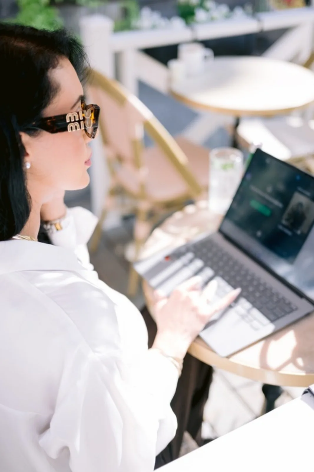 Stéphanie Nachar travaillant sur son ordinateur portable sur une terrasse ensoleillée.